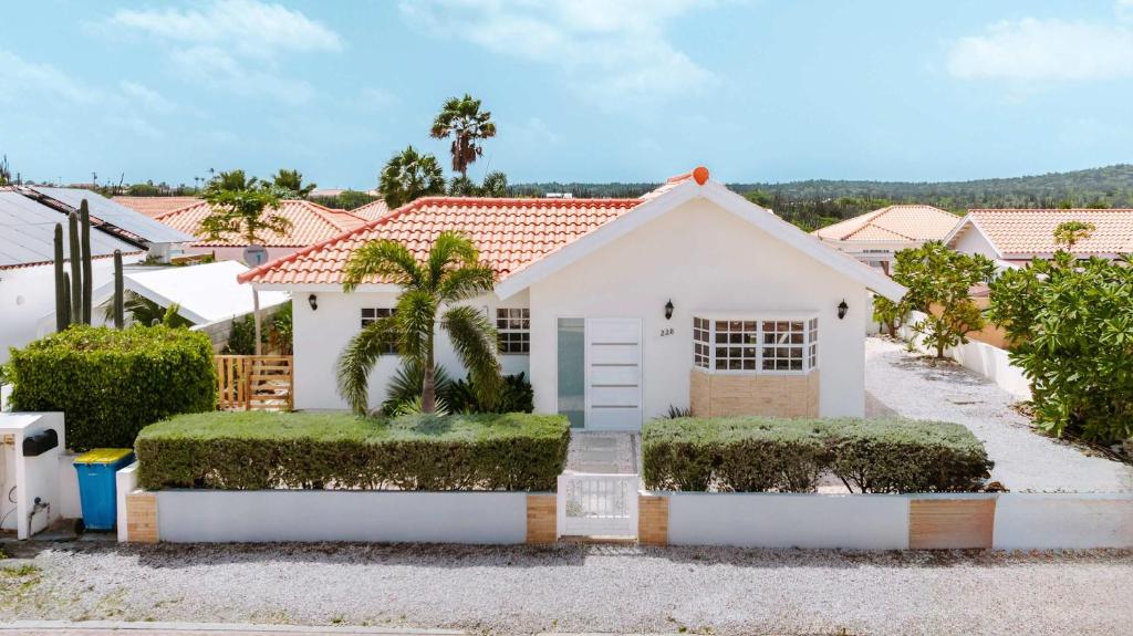 a white house with bushes in front of it at Casa del Sol, 2-Bedroom Home Near Palm Beach in Noord