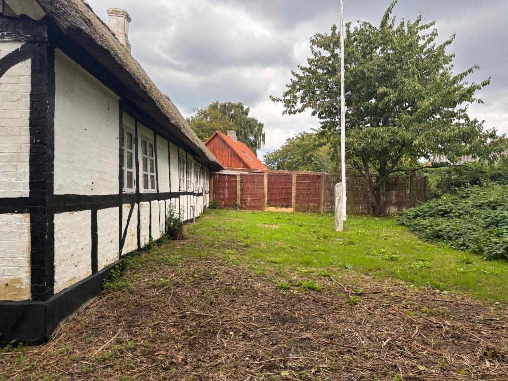 an old building with a grass yard next to a fence at Hans Christian Andersen Eventyrhuset in Bogense