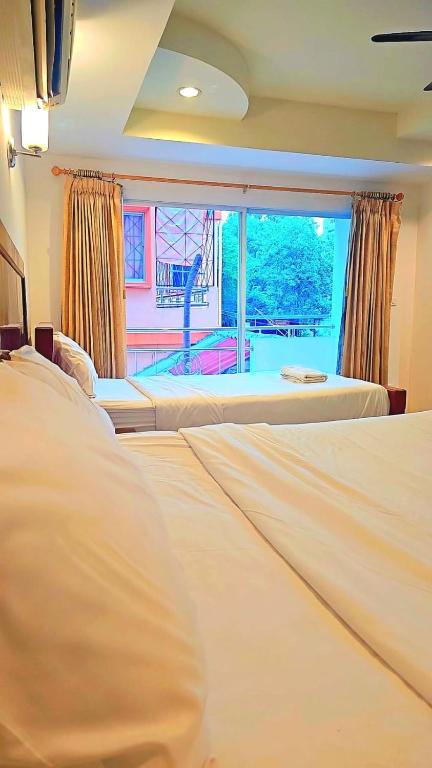a bedroom with two beds and a large window at Home 24 Pattaya in Pattaya