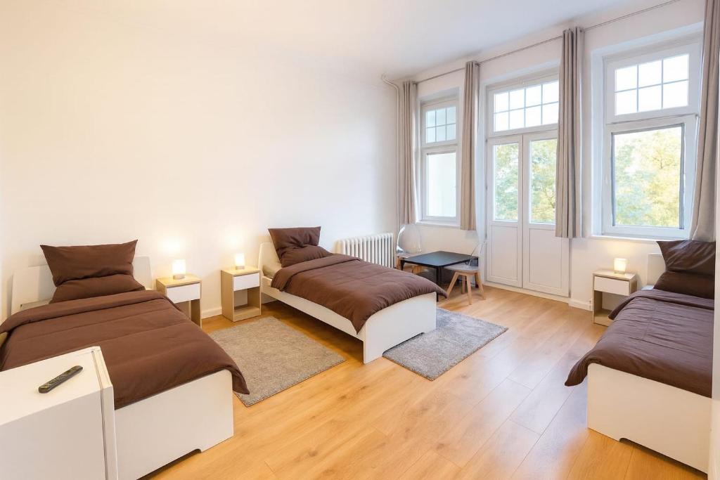 a bedroom with two beds and two windows at Hostelion in Magdeburg