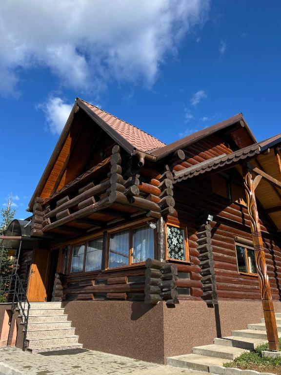 a log cabin with stairs in front of a house at Casa Brindusa in Poiana Negrii