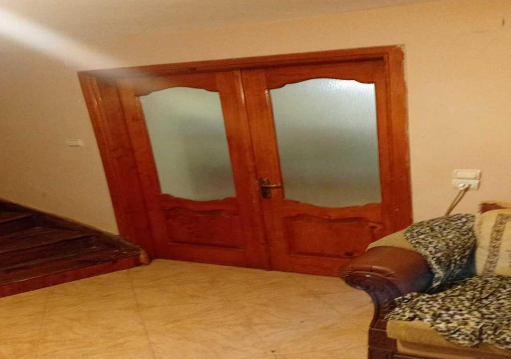 a room with two wooden doors and a couch at Business Hostel in Korçë