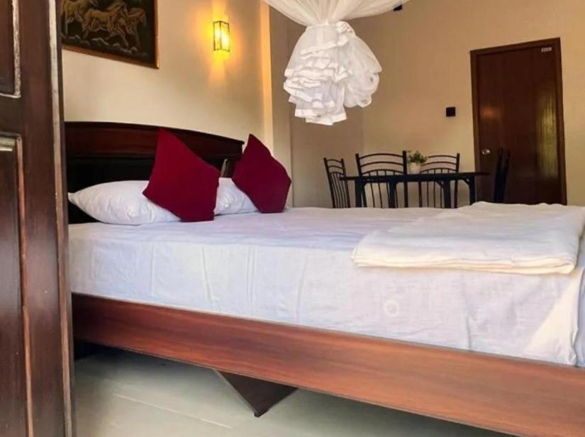 a large bed with white sheets and red pillows at Royal Grand Guest Inn Ella in Ella
