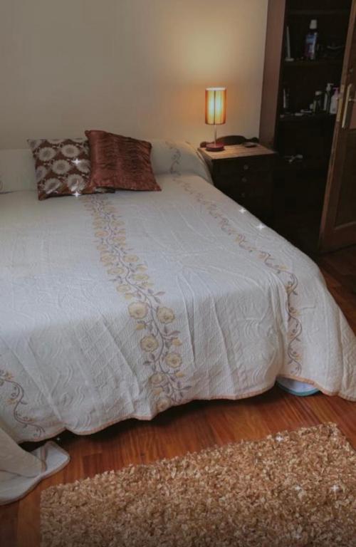 1 dormitorio con cama blanca y alfombra en Vigohose, en Vigo