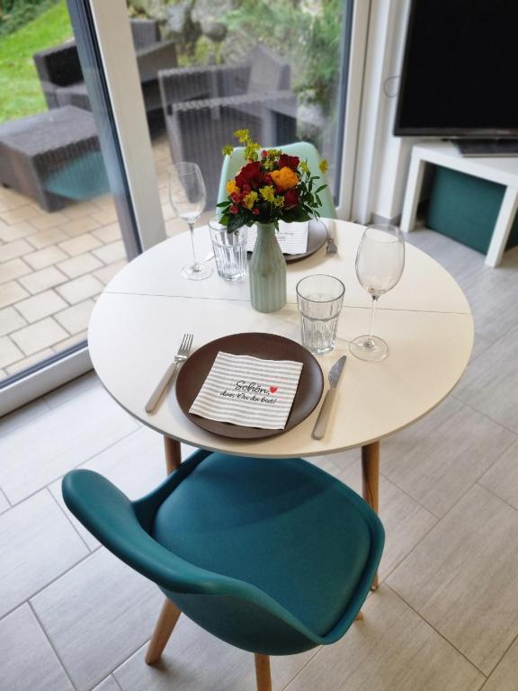 a white table with a blue chair and a table with wine glasses at HO home in Ochsenhausen