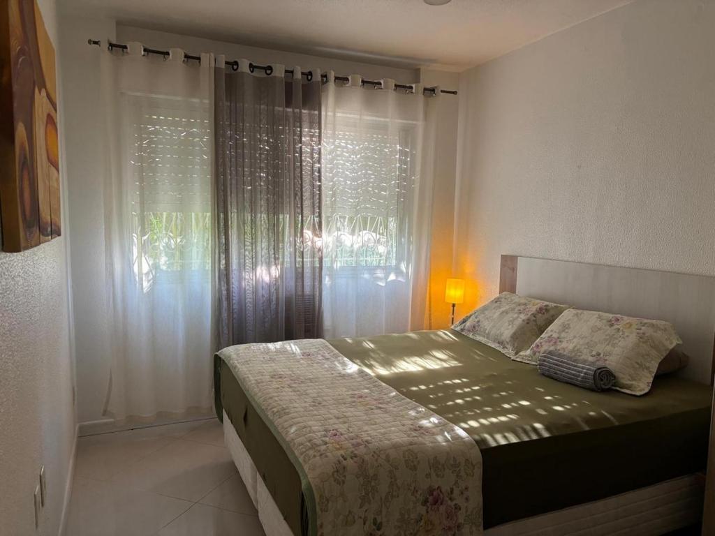 une chambre avec un lit et une fenêtre avec des rideaux dans l'établissement Prático e Aconchegante, à Porto Alegre