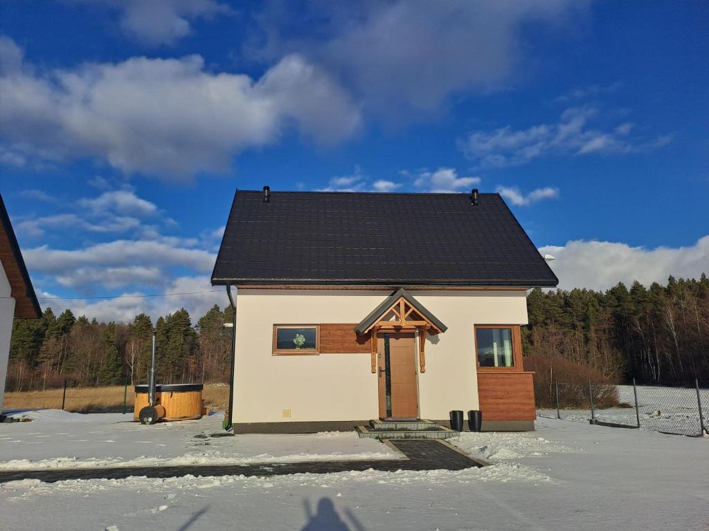 ein kleines Haus mit schwarzem Dach im Schnee in der Unterkunft Leśny Zakątek Brzezinki 