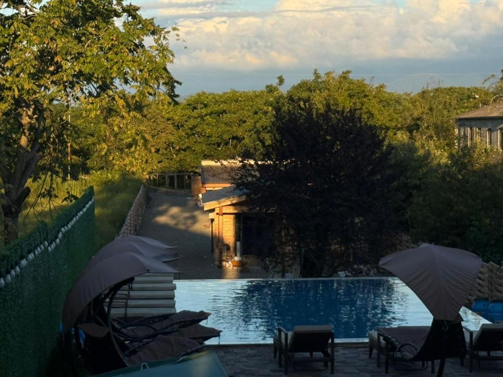 a swimming pool with umbrellas and chairs next to a building at Meidan Oda Holiday Homes in K'obulet'i