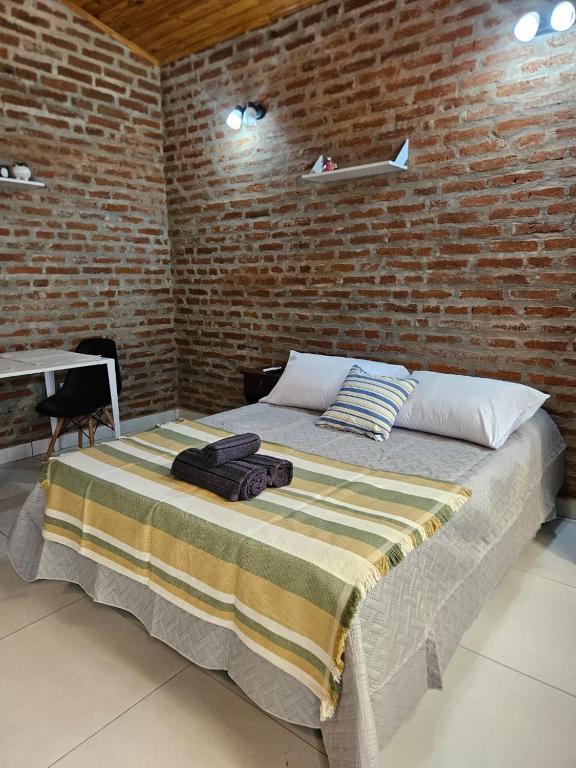 a bed in a room with a brick wall at Acogedor loft estilo industrial in Posadas