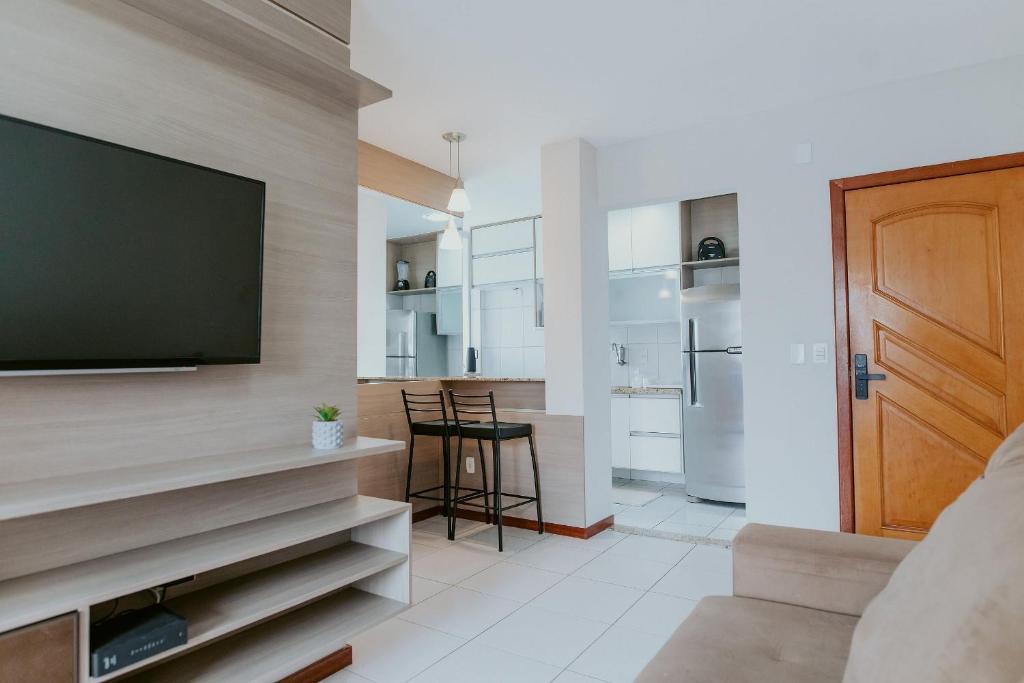 a living room with a flat screen tv on a wall at Apto Aconchegante em Jardim Camburi in Camburi
