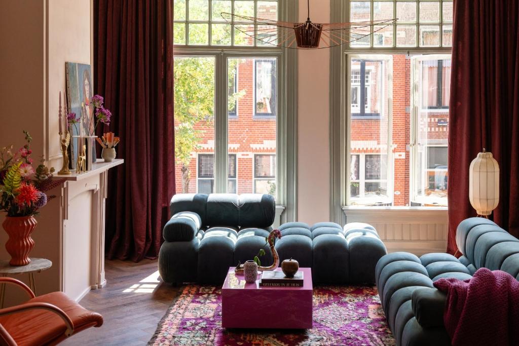 a living room with blue furniture and large windows at Luxurious boutique apartment near city centre in Groningen