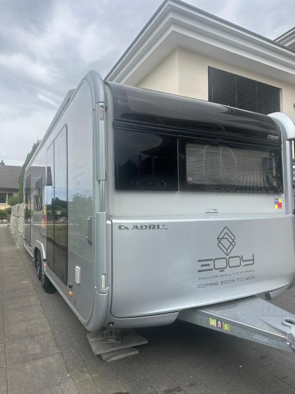 a large silver trailer parked in front of a house at Beautiful, luxurious Caravane property in Rothrist