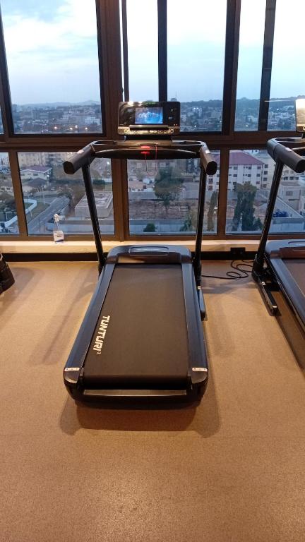 a room with a treadmill in front of a large window at Real Homes 2 bedroom Nova Apartments in Accra