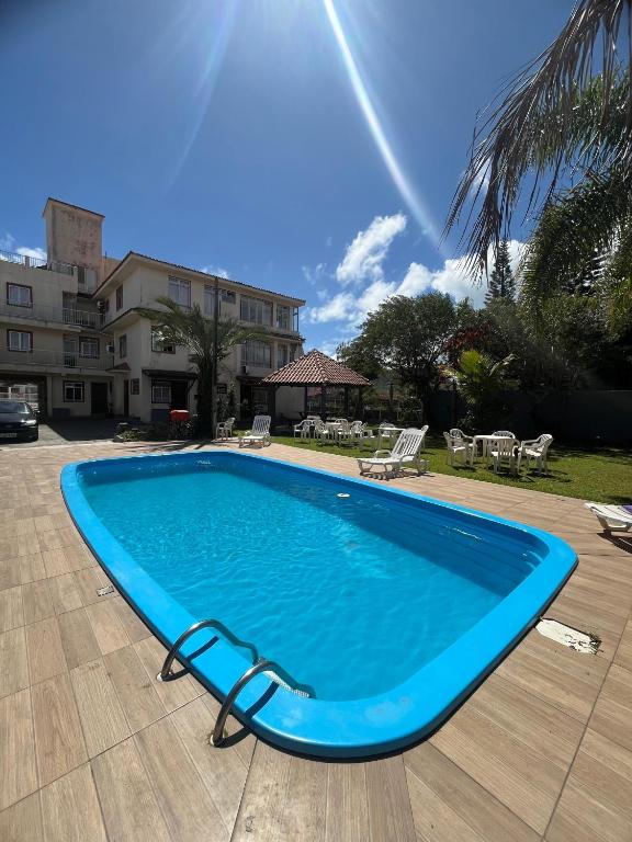 a large blue swimming pool in a yard at Hotel e Pousada Recanto do mar in Florianópolis