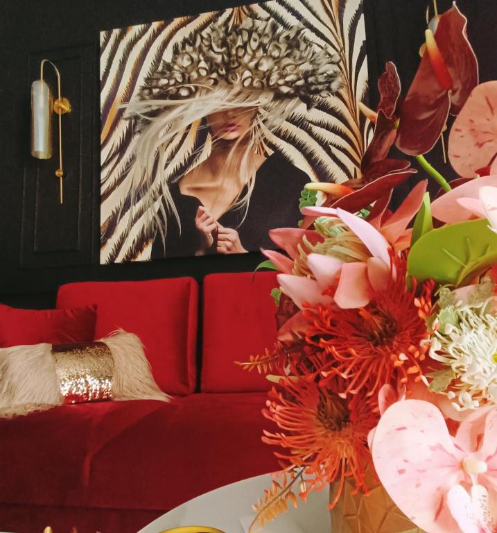 a living room with a red couch and flowers at El Jardín de las Libélulas in Coria