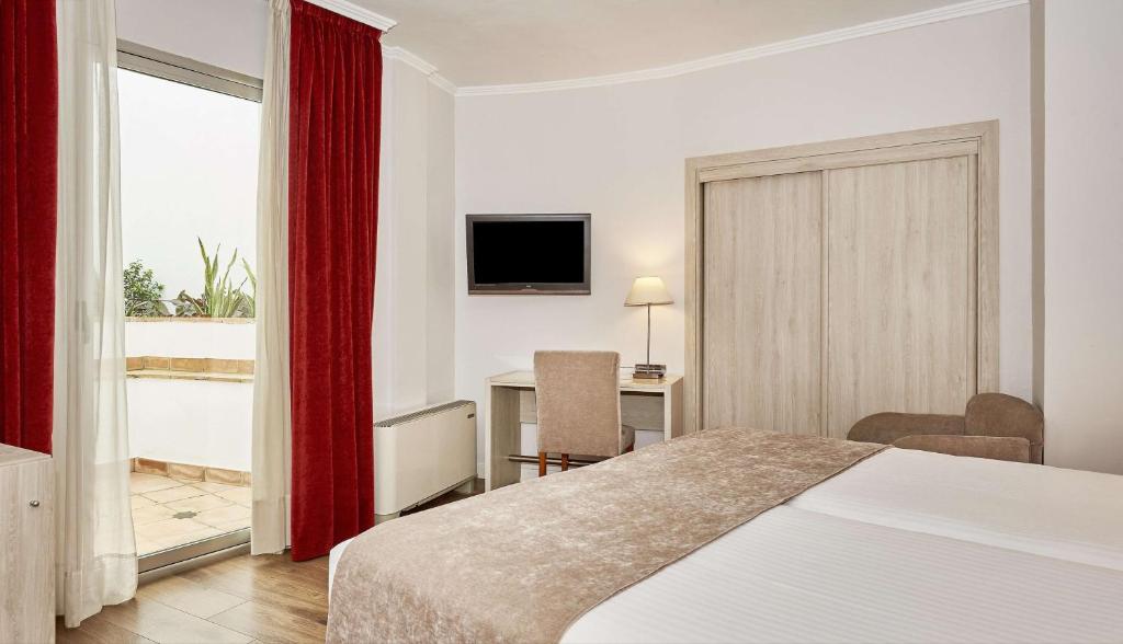 a hotel room with a bed and a desk and a television at NH Córdoba Califa in Córdoba