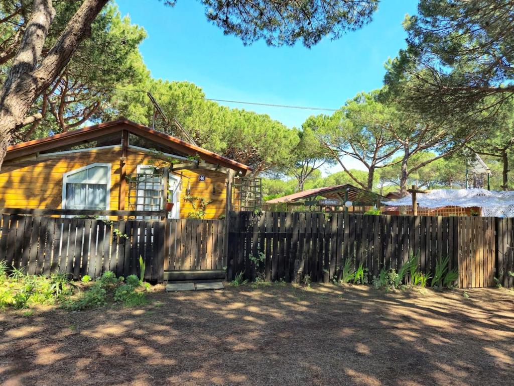 a yellow house behind a wooden fence at La Cabane Caparica in Charneca