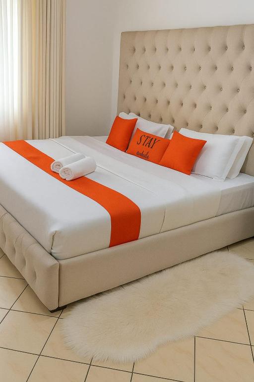 a bed with orange and white pillows on it at SarafuDeluxe in Nakuru