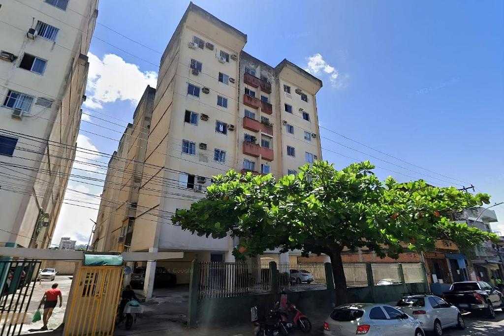 a tall building with a tree in front of it at Condomínio Aldeia do Rádio in Carmo