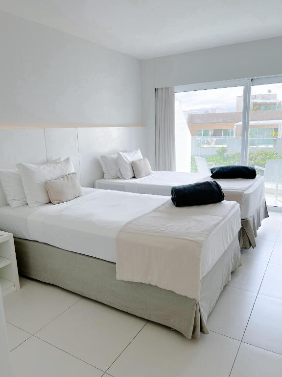 zwei Betten in einem weißen Zimmer mit Fenster in der Unterkunft CDesign Hotel in Rio de Janeiro