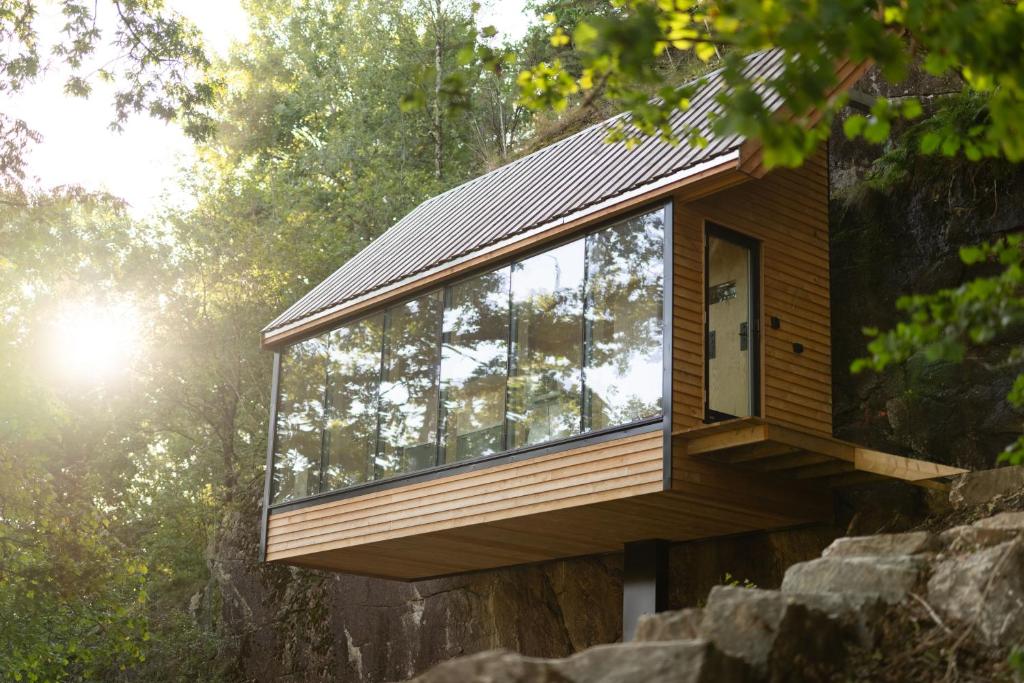 a glass house on a rock in the forest at Backyard Camps in Bjerkreim