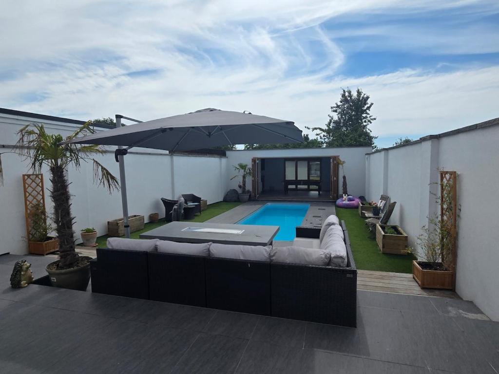 a patio with a couch and an umbrella and a pool at Villa at 58 London Rd in Amesbury