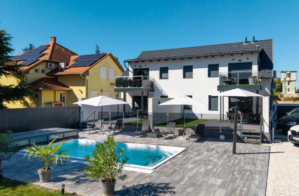 a swimming pool with umbrellas next to a building at Bala-Home Apartments & Pool in Balatonboglár