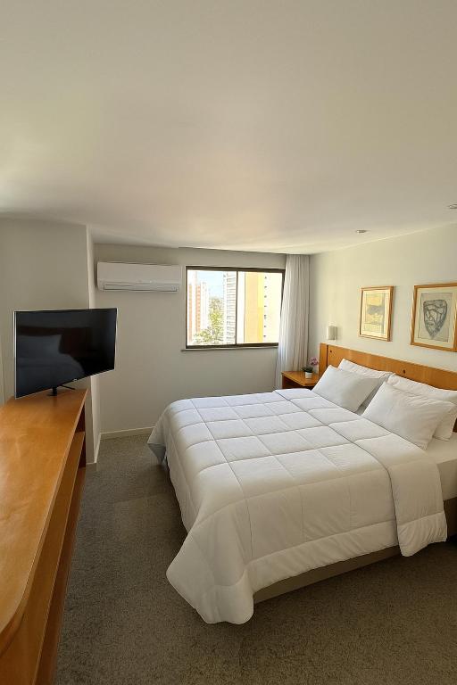 a bedroom with a large white bed and a flat screen tv at 1506 - Blue Tree Towers in Fortaleza