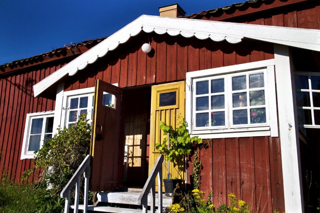 a red house with a yellow door and windows at Pensionat Hogården in Boxholm