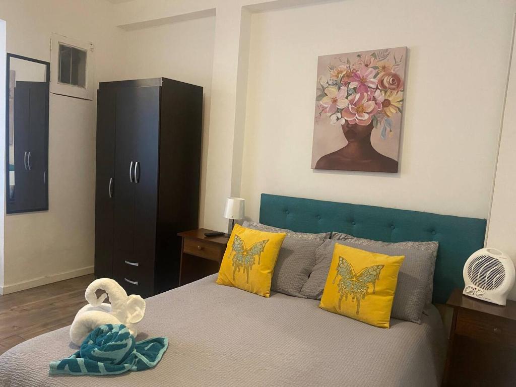 a bedroom with a bed with a blue headboard and yellow pillows at Home Estudio 3 in Santiago