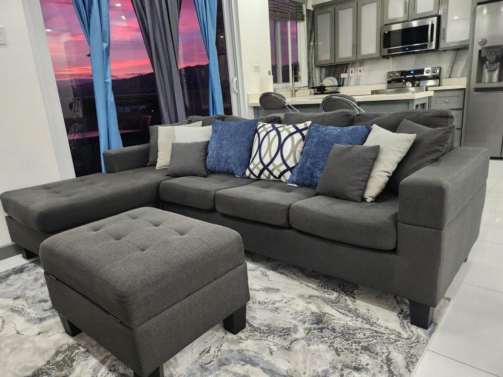 a living room with a couch and a ottoman at Modern Kingston Condo with Rooftop Pool and View in Kingston
