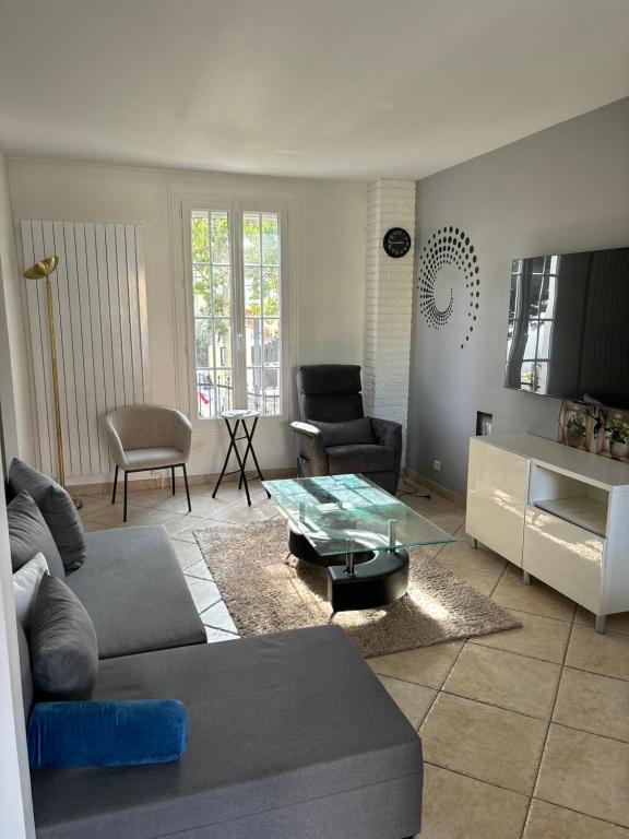 a living room with a couch and a table at Maison moderne avec jardin espace télétravail in Bobigny