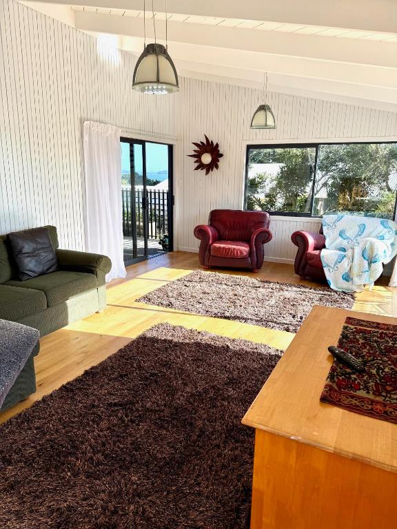 a living room with a couch and chairs and a table at Sandy Beach Apartment in Russell
