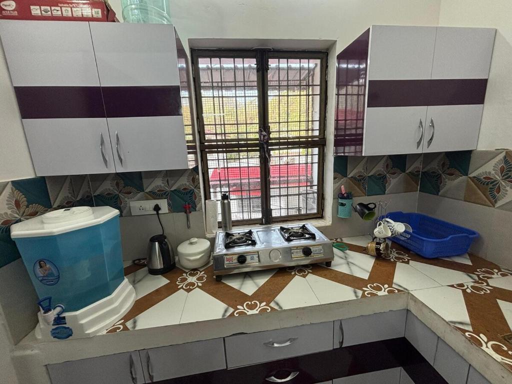 a kitchen with white cabinets and a stove in it at Naini Kalsa Stay in Nainital