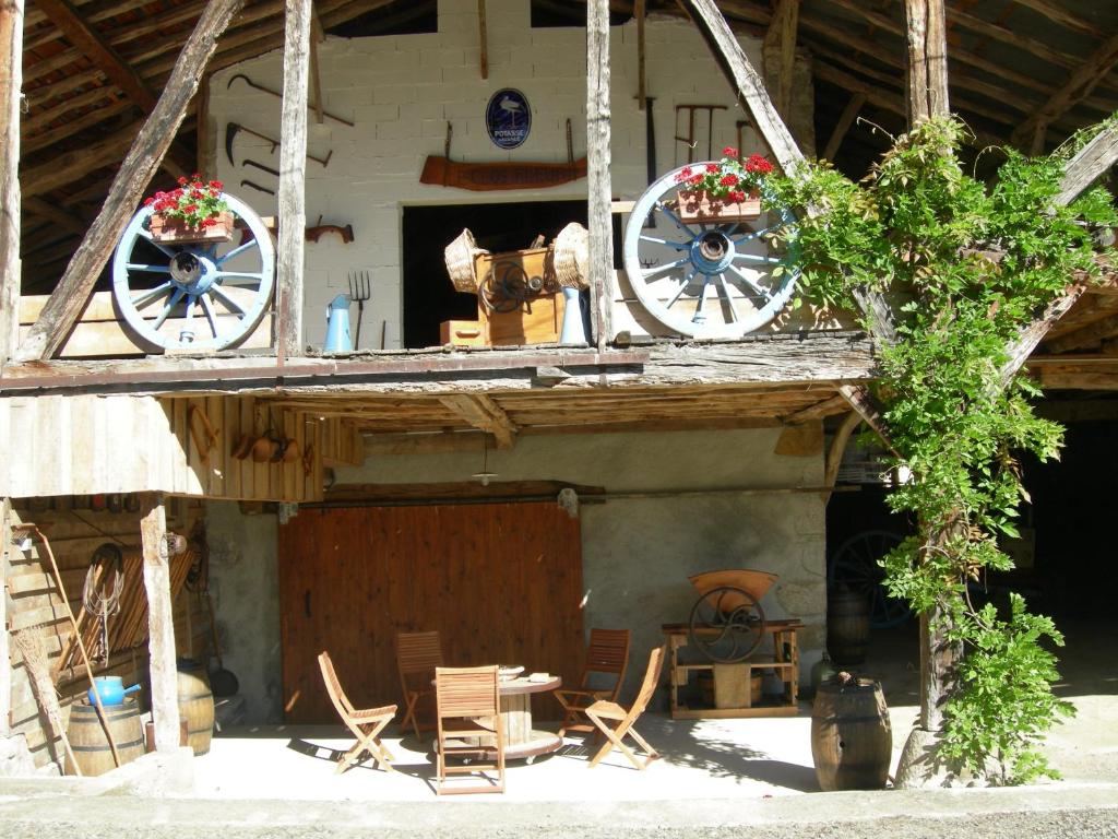 a house with two wagon wheels and chairs and a table at Le Clos Fleuri in Caumont