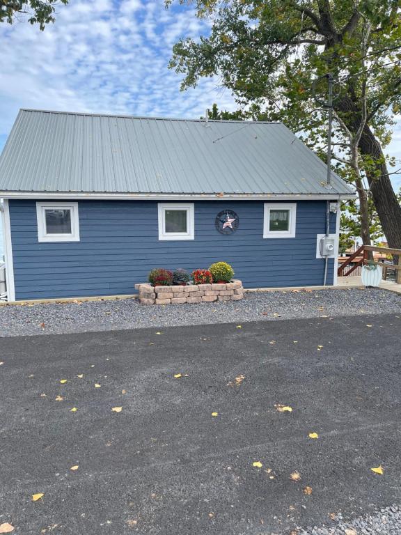 ein blaues Haus mit zwei Fenstern und zwei Pflanzen davor in der Unterkunft Year-round Cozy Cottage Charm on Cayuga Lake in Romulus