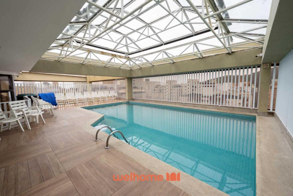 a large swimming pool in a building with a glass ceiling at Apto em Guarujá a 3 min a pe da Praia Pitangueiras in Guarujá