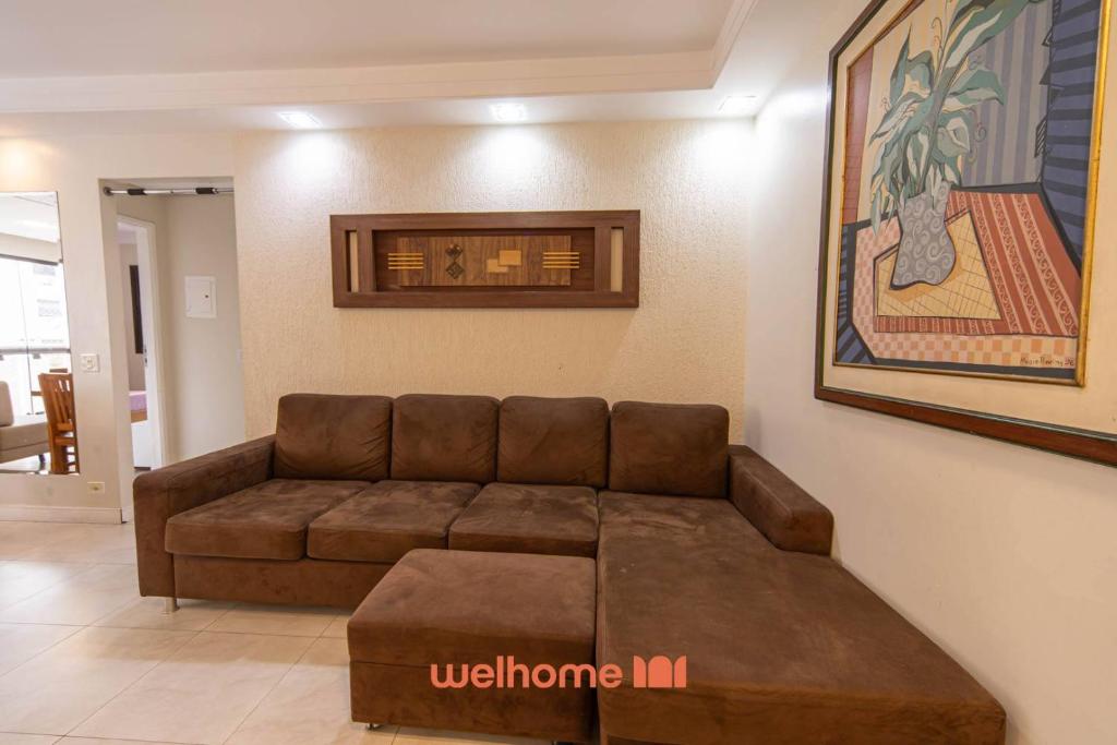 ein Wohnzimmer mit einer braunen Couch in einem Zimmer in der Unterkunft Apto Praia das Pitangueiras com Piscina aquecida in Guarujá