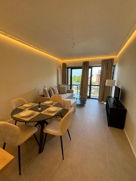 a living room with a table and chairs and a couch at Luxury 1 Bedroom Apartment with Sofa Bed & Balconies Prime Location near ING Arena, Expo 12 & Atomium in Wemmel