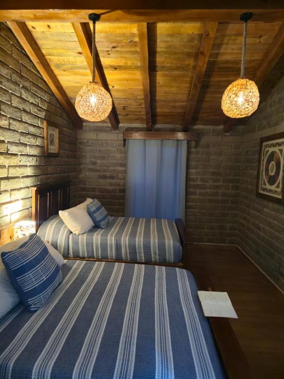 two beds in a room with wooden ceilings and lights at Cabaña el rio Rincon Verde in Tomatlán