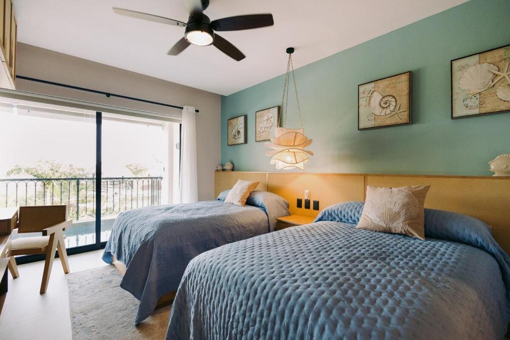 two beds in a bedroom with green walls and a window at Maritime Apartment Sea View in Huatulco, 2 Rec in Bahías de Huatulco