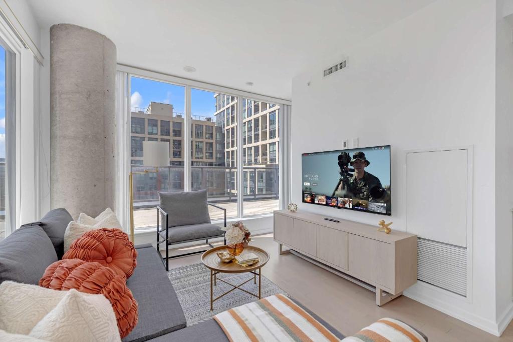 a living room with a couch and a flat screen tv at Prime 2BR Condo with Massive Patio & Parking in Toronto