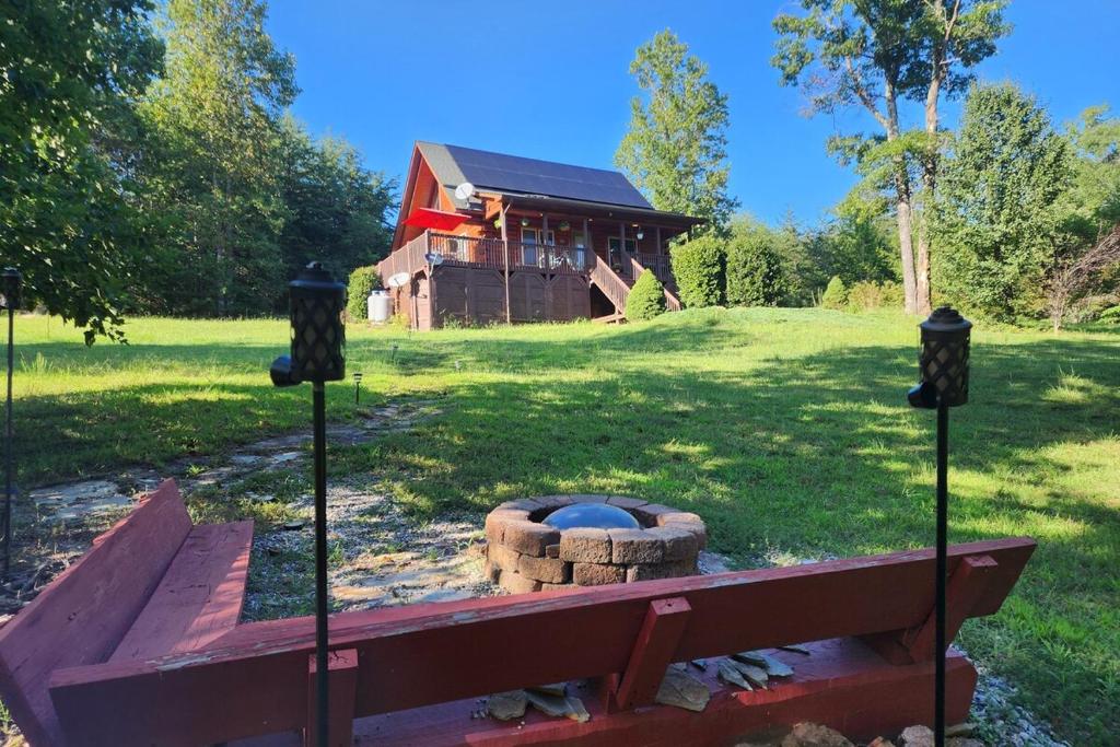 a fire pit in front of a house at Solar powered log cabin with mountain views, 3acres in Lake Lure