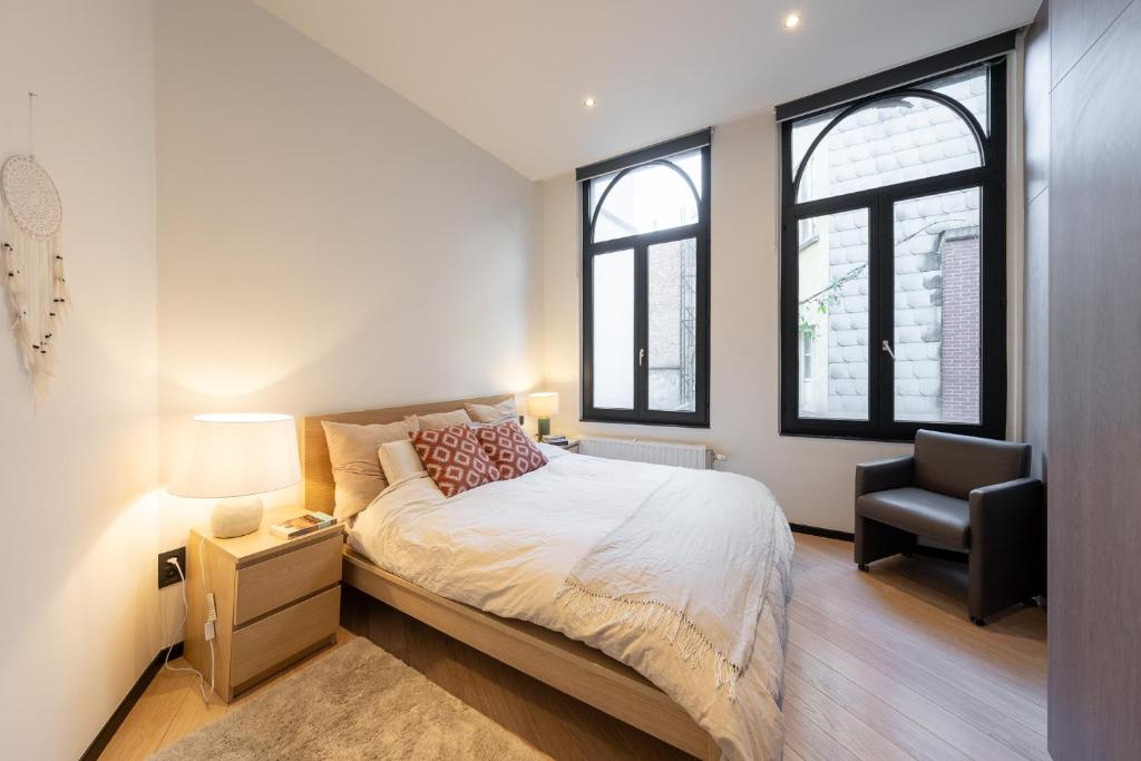 een slaapkamer met een bed, een stoel en ramen bij A Marbled Touched Haven in Antwerpen