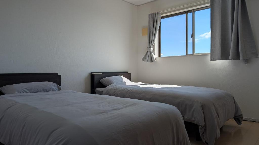 two beds in a room with a window at Yomitan 4LDK house in Yomitan