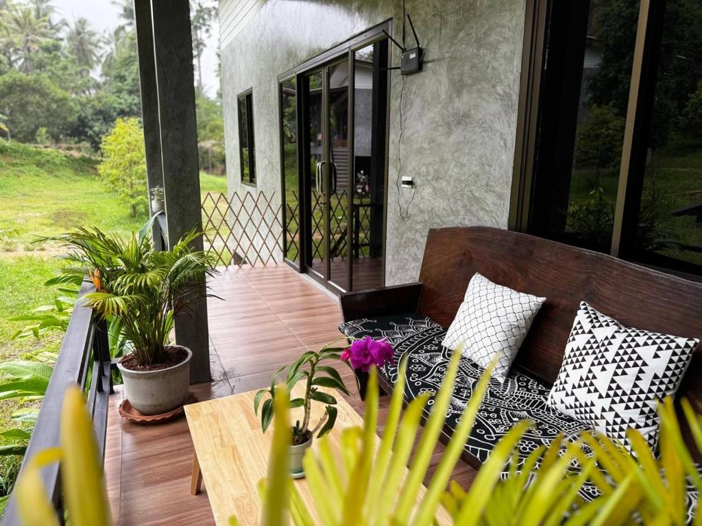 Un patio con un sofá en un porche con plantas. en Bantai Hideaway - House 2, en Ko Phangan