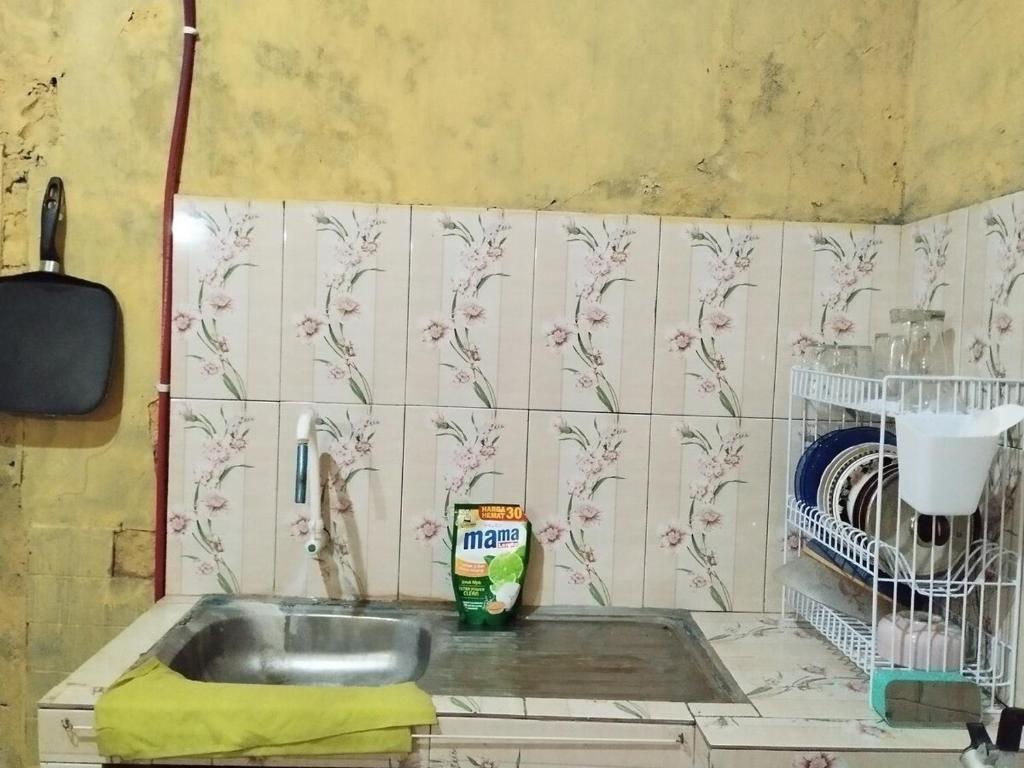 una cucina con lavandino e parete piastrellata di 563 Homestay Jogja a Ngabean