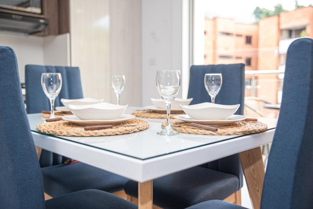 a dining table with glasses and plates and chairs at Apartahotel Ginebra central cerca laureles in Medellín