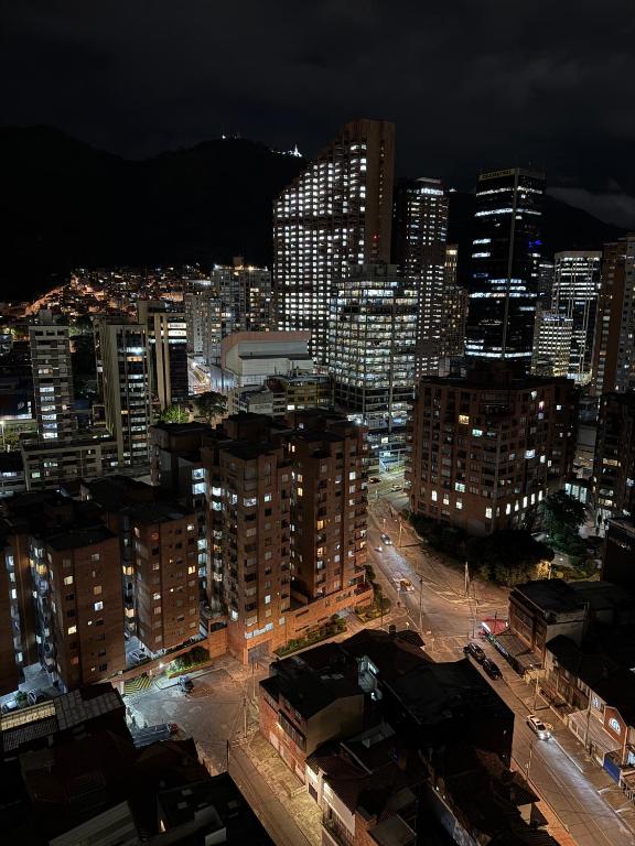 a city lit up at night with tall buildings at Modern apartment with a beautiful panoramic view in Bogotá