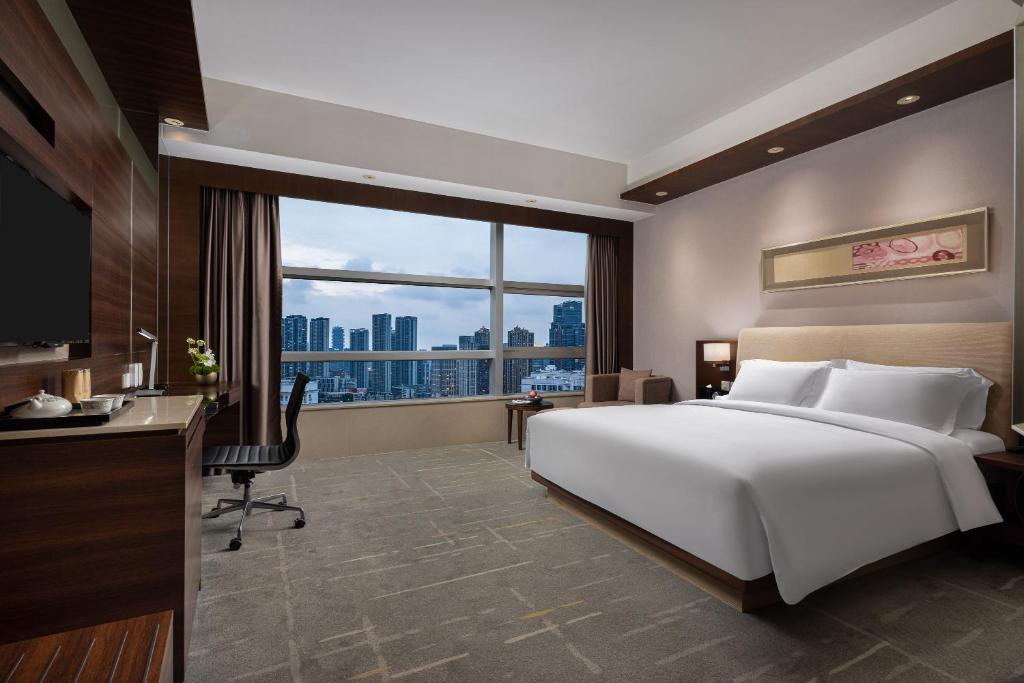 Una habitación de hotel con una cama, un escritorio y una ventana. en New World Wuhan Hotel, en Wuhan